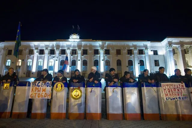 Members of Crimean self-defence units stand guard in front of the local government headquarters in Simferopol March 2, 2014. Ukraine mobilised for war on Sunday and Washington threatened to isolate Russia economically, after President Vladimir Putin declared he had the right to invade his neighbour, creating Moscow's biggest confrontation with the West since the Cold War. (Photo by Thomas Peter/Reuters)