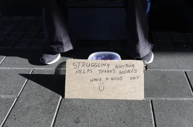 A man sits with a bowl asking for money in the central business district of Christchurch, New Zealand, Thursday, May 30, 2019. The liberal-led government on Thursday unveiled the country's first so-called well-being budget, which aims to measure social outcomes like health and the environment alongside traditional metrics such as economic growth. (Photo by Mark Baker/AP Photo)