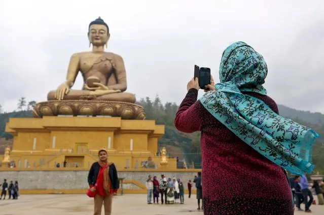 Tourists take photos beside the Buddha Dordenma statue in the town of Thimphu, Bhutan, April 16, 2016. (Photo by Cathal McNaughton/Reuters)