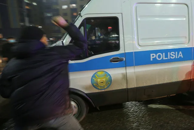 A man attacks a police minivan during a protest against LPG cost rise following the Kazakh authorities' decision to lift price caps on liquefied petroleum gas in Almaty, Kazakhstan on January 4, 2022. (Photo by Pavel Mikheyev/Reuters)