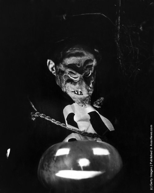 A masked guest with a pumpkin at a fancy dress halloween party given to welcome American actress Barbara Bates to Britain