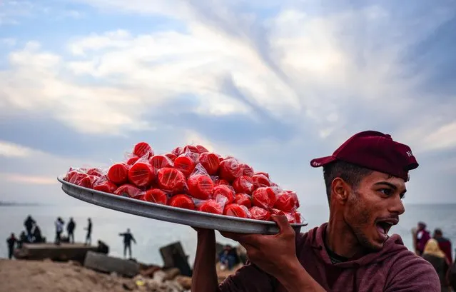 A Palestinian vendor yells to attract customers as he sells sugar-coated apples along the beach in Gaza city, on January 6, 2022. (Photo by Mohammed Abed/AFP Photo)