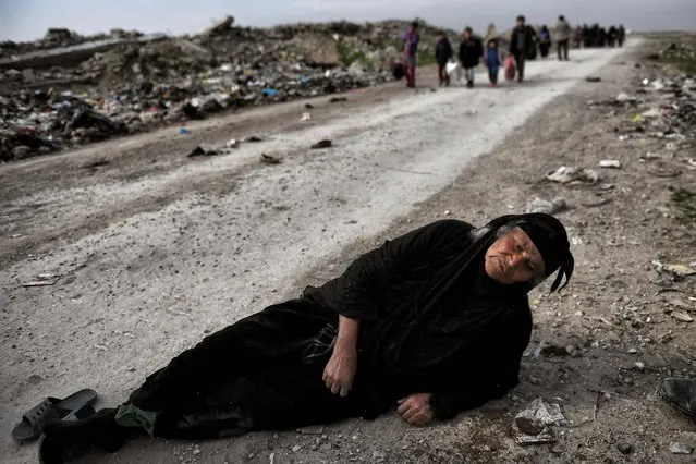 An Iraqi woman lies on the ground as civilians flee Mosul while Iraqi forces advance inside the city during fighting against Islamic State group's fighters on March 8, 2017. Supported by US-led air strikes, the forces have made steady progress in their battle to seize Iraq's second city from the Islamic State group, announcing the recapture of two more areas. Hundreds of thousands of civilians are believed to still be trapped under jihadist rule in the Old City, where Abu Bakr al-Baghdadi proclaimed a “caliphate” in his only public appearance in July 2014. (Photo by Aris Messinis/AFP Photo)