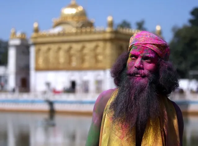 A Sadhu or Hindu holy man with his face smeared with powdered colors looks on during Holi festival celebrations at Sri Laxmi Narayan Temple in Amritsar, India, 12 March 2017. Holi is celebrated at the end of the winter season on the last full moon day of the lunar month Phalguna, which usually falls in the later part of February or March and is celebrated by people throwing colored powder and colored water at each other. (Photo by Raminder Pal Singh/EPA)