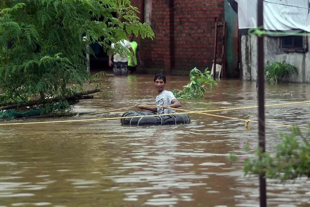 A man uses a tyre tube to wade through a water-logged road after heavy rains in Badlapur, in Maharashtra, July 27, 2019. (Photo by Francis Mascarenhas/Reuters)