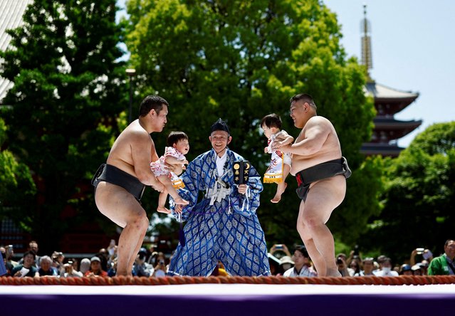 Amateur sumo wrestlers hold babies during “Nakizumo” or a baby-crying sumo contest, where two wrestlers hold a baby each and a referee makes faces and loud noises to make them cry and determine the winner based on the loudest baby, at Sensoji temple in Tokyo, Japan, on April 28, 2024. The ritual is believed to aid the healthy growth of the children and ward off evil spirits. (Photo by Issei Kato/Reuters)