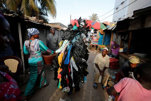 Modou Fall, 43, head of Senegal Propre (“Clean Senegal”) Association who is covered with plastic cups and bags to raise awareness of the damage on the environment caused by plastic waste talks to residents in a market on the outskirts of Dakar, Senegal on July 26, 2019. (Photo by Zohra Bensemra/Reuters)