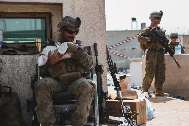 A U.S. Marine assigned to the 24th Marine Expeditionary Unit (MEU) holds a baby during an evacuation at Hamid Karzai International Airport, Kabul, Afghanistan, August 20, 2021. (Photo by Sgt. Isaiah Campbell/U.S. Marine Corps/Handout via Reuters)