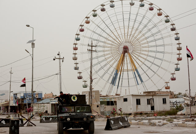Iraqi counterterrorism forces drive past a ferris wheel in a central district of Ramadi on March 20, 2016. Months after being wrested from the control of the Islamic State group, Ramadi remains devastated with no running water or electricity, entire residential blocks destroyed and no clear picture on when or how it can be rebuilt. (Photo by Maya Alleruzzo/AP Photo)