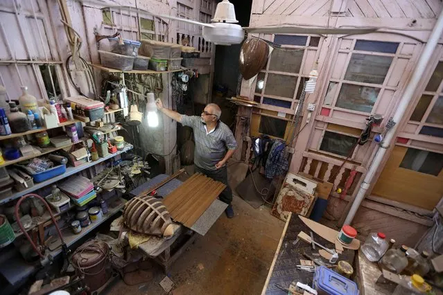 In this photo taken Thursday, June 18, 2015,  Oud maker Mahmoud Abdulnabi works in his shop in Baghdad, Iraq. Abdulnabi is one of the last craftsmen in Baghdad who carves ouds by hand. “Our brothers, the makers in Syria, Turkey and Egypt, might produce 12 pieces a day using machines”, Abdulnabi said. “We produce one or two pieces in a month”. (Photo by Hadi Mizban/AP Photo)
