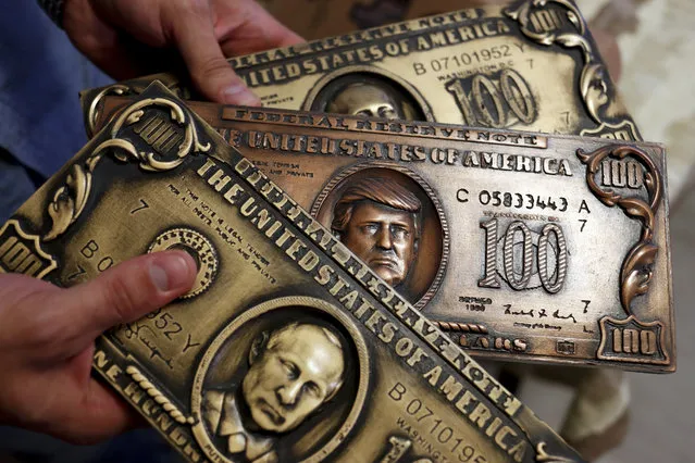 Russian hacker Sergey Pavlovich, better known by his former online alias Police Dog, holds a mock money printing plate with Russian President Vladimir Putin, bottom, and US President Donald Trump, center, faces in place of Benjamin Franklin during an interview with the Associated Press in Moscow, Russia, Wednesday, August 9, 2017. (Photo by Pavel Golovkin/AP Photo)