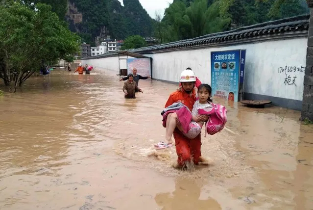 This photo taken on May 8, 2016 shows rescue workers helping residents make their way through floodwaters after strong rains hit Yangshuo county, south China's Guangxi province. Heavy rainfall pounded south China's Guangxi Zhuang Autonomous Region, leaving hundreds of villagers and tourists trapped in the worst-hit parts of the region on May 8, state media reported. (Photo by AFP Photo/Stringer)