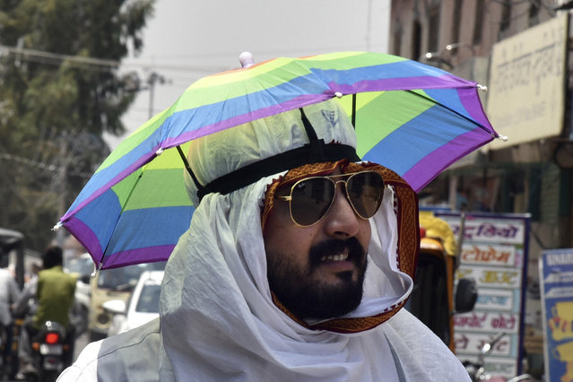 A man wears an umbrella hat on a hot summer day in Bikaner, in the Indian western state of Rajasthan, Thursday, May 23, 2024. (Photo by Dinesh Gupta/AP Photo)