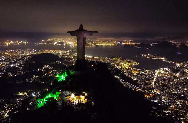 An aerial image taken by a drone shows an unlit Christ the Redeemer statue, in Rio de Janeiro, Brazil, 25 March 2023. The famous monument had its lights shut off in support of Earth Hour 2023, organized by the World Wildlife Fund (WWF), with the goal of bringing attention to the climatic crisis. (Photo by Andre Coelho/EPA)