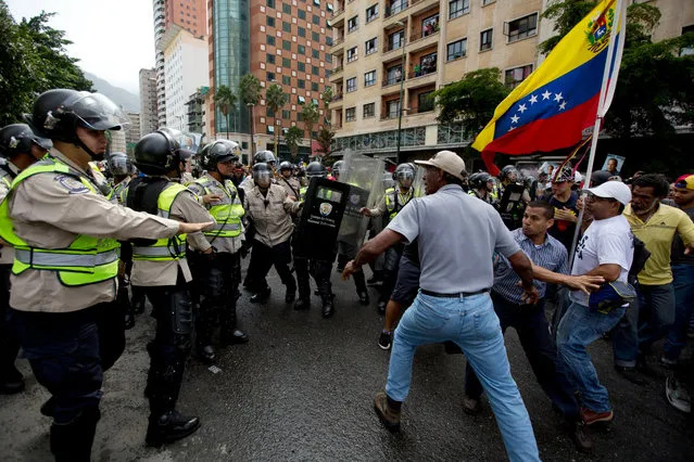 Anti-government demonstrators try to break through a barrier of Bolivarian National Police in an effort to reach the headquarters of the national electoral body, CNE, in Caracas, Venezuela, Wednesday, May 18, 2016. (Photo by Fernando Llano/AP Photo)