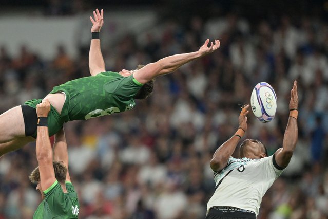 Ireland's Hugo Keenan (L) reaches to catch the ball as he is challnged by Fiji's Iosefo Baleiwairiki (R) during the men's quarter final rugby sevens match between Fiji and Ireland during the Paris 2024 Olympic Games at the Stade de France in Saint-Denis on July 25, 2024. (Photo by Carl de Souza/AFP Photo)