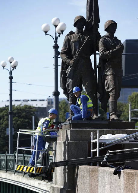 Workers prepare to dismantle Soviet era statues from the Green Bridge over the Neris river in Vilnius, Lithuania, Sunday July 19, 2015. Statues depicting Red Army soldiers, workers, students and peasants were erected on the historic Green Bridge over the River Neris in 1952, 12 years after the Soviet Union occupied Lithuania and its Baltic neighbors, Latvia and Estonia. (Photo by Mindaugas Kulbis/AP Photo)