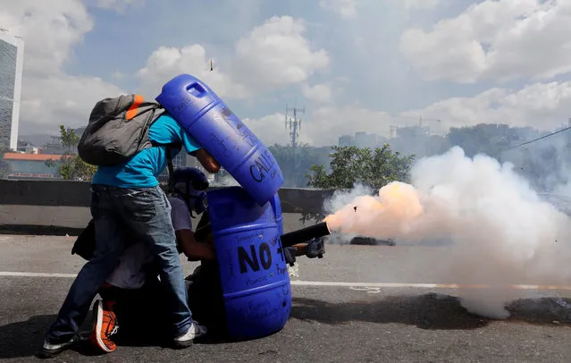 Opposition supporters uses a home made mortar while clashing with riot security forces during a rally against President Nicolas Maduro in Caracas, Venezuela, May 18, 2017. (Photo by Carlos Garcia Rawlins/Reuters)