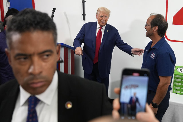 Republican presidential nominee former President Donald Trump, center, speaks with a supporter during a stop at a campaign office, Monday, August 26, 2024, in Roseville, Mich. (Photo by Carolyn Kaster/AP Photo)