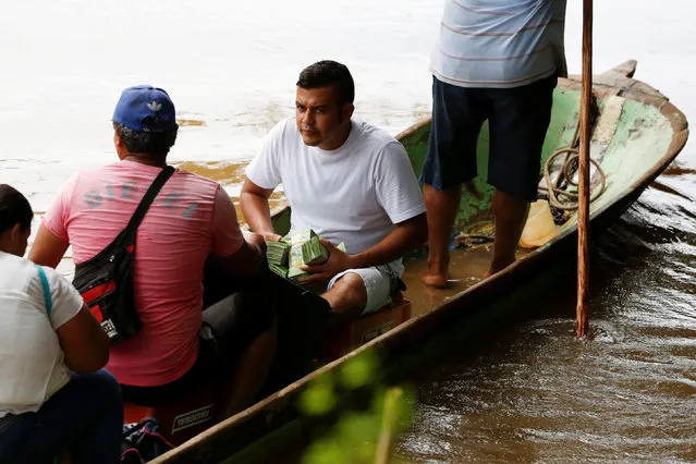 A man carries stacks of Venezuelan bolivar notes as he crosses in a canoe to Boca del Grita in Venezuela, across the border from Puerto Santander, Colombia, June 3, 2016. Picture taken from the Colombia side of the Venezuela-Colombia border. (Photo by Carlos Garcia Rawlins/Reuters)