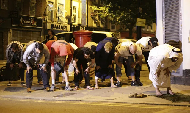 Local people observe prayers at Finsbury Park where a vehicle struck pedestrians in London Monday, June 19, 2017. Police say a vehicle struck pedestrians near a mosque in north London, leaving several casualties and one person was arrested. (Photo by Yui Mok/PA Wire via AP Photo)