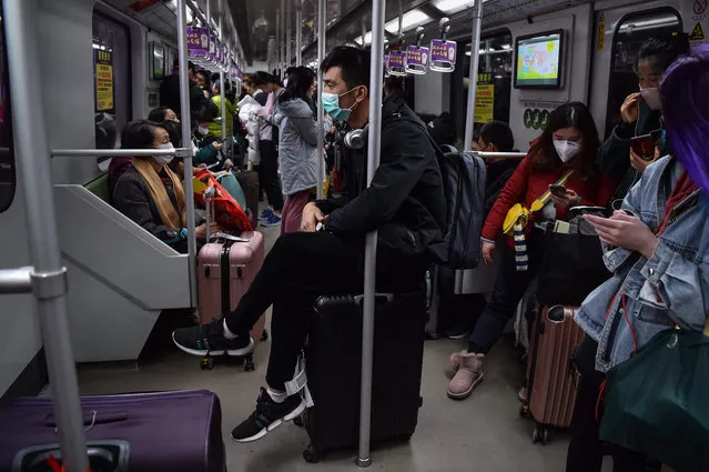 A man wearing a protective mask sits on luggage as he travels on the subway in Shanghai on January 22, 2020. A new virus that has killed nine people, infected hundreds and already reached the United States could mutate and spread, China warned January 22, as authorities scrambled to contain the disease during the Lunar New Year travel season. (Photo by Hector Retamal/AFP Photo)