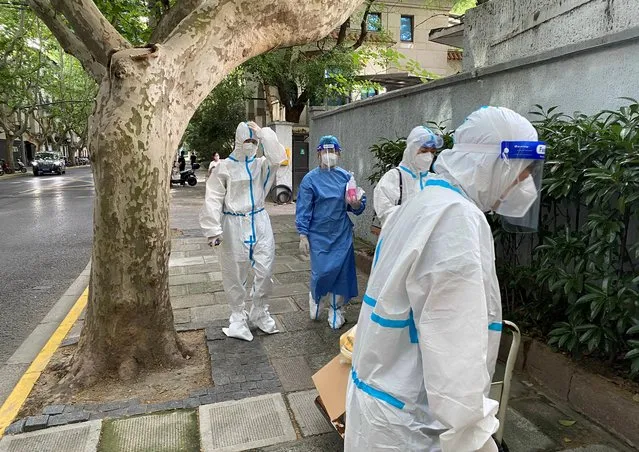 Workers in protective suits walk on a street, following the coronavirus disease (COVID-19) outbreak, in Shanghai, China on June 9, 2022. (Photo by Andrew Galbraith/Reuters)