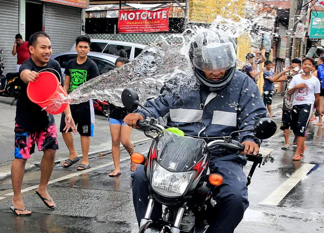 A man throws a bucket of water at a motorcyclist as residents join in a water-splashing frenzy to honor their patron St. John the Baptist's Feast Day in San Juan, Metro Manila, Philippines June 24, 2016. (Photo by Romeo Ranoco/Reuters)