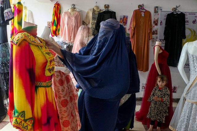 An Afghan burqa-clad woman checks a dress at a shop in Fayzabad district of Badakhshan province on October 16, 2023. (Photo by Omer Abrar/AFP Photo)