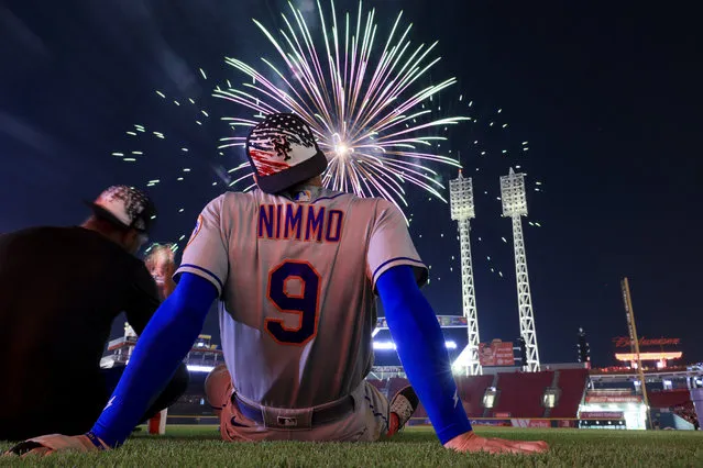 New York Mets' Brandon Nimmo (9) sits on the field to watch fireworks after a baseball game against the Cincinnati Reds in Cincinnati, Monday, July 4, 2022. (Photo by Aaron Doster/AP Photo)