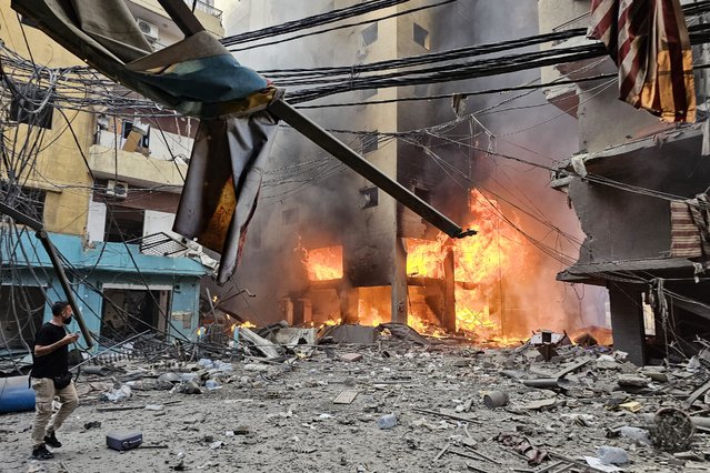 A man walks over the debris as a fire rages inside a building hit by an Israeli airstrike that targeted the neighbourhood of Haret Hreik in Beirut's southern suburbs on November 21, 2024, amid the ongoing war between Israel and Hezbollah. (Photo by AFP Photo/Stringer)