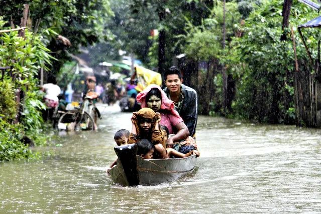 Local residents ride a boat on a flooded road overflown by the Bago river at a low-lying part in Bago, 80 kilometers (50 miles) northeast of Yangon, Myanmar, Monday, August 4, 2014. Flooding is common during Myanmar's monsoon season, which typically starts in late May and ends in mid-October. (Photo by Khin Maung Win/AP Photo)