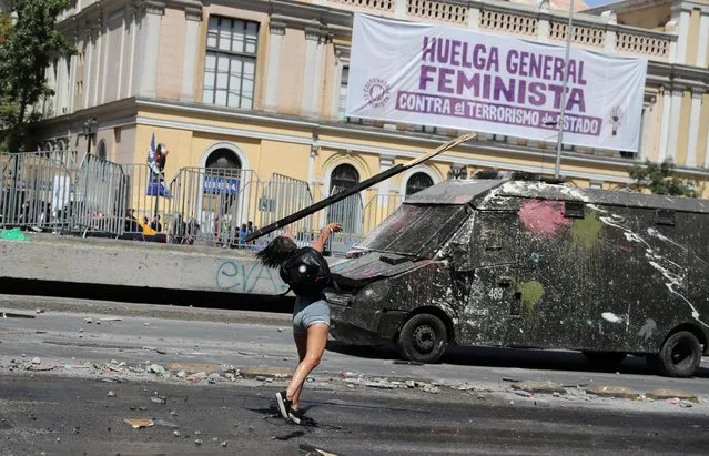 A woman throws a stick toward a riot police vehicle during a women's strike as part of International Women's Day activities in Santiago, Chile on March 9, 2020. (Photo by Ivan Alvarado/Reuters)