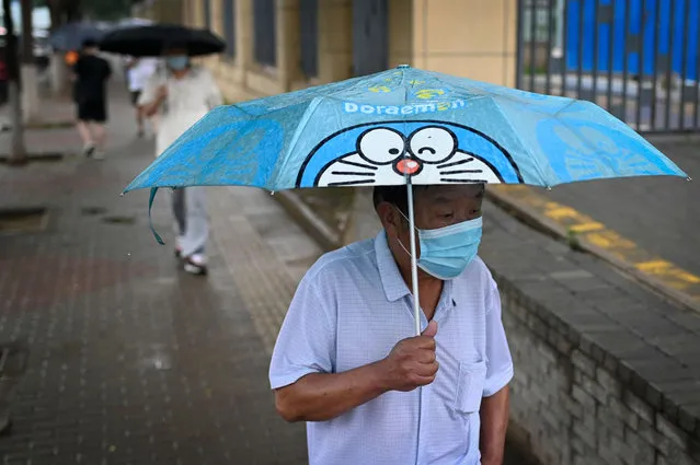 An elderly man walks along a street on a rainy day in Beijing on June 27, 2022. (Photo by Wang Zhao/AFP Photo)