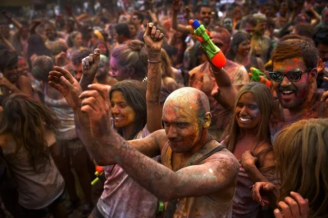 Revelers of the Holi Festival of Colors dance after throwing colored powders in the air in Madrid, Spain, Saturday, August 9, 2014. The festival is fashioned after the Hindu spring festival Holi, which is mainly celebrated in the north and east areas of India. (Photo by Daniel Ochoa de Olza/AP Photo)