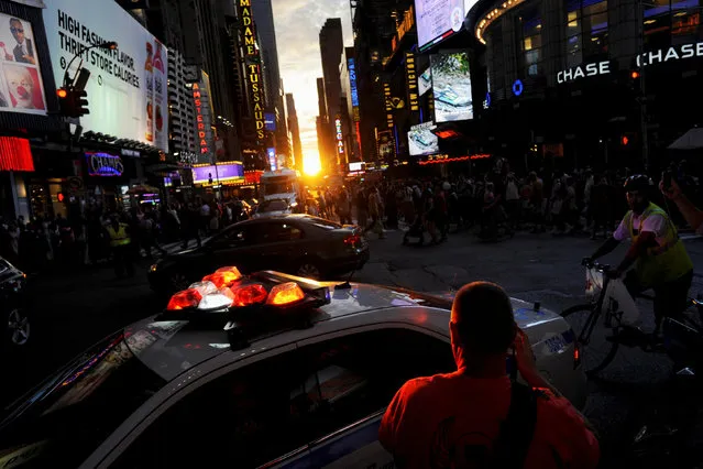A police car passes, telling people to leave the street as the sun sets over Manhattan aligned exactly with the streets in a phenomenon known as “Manhattanhenge”, in New York City, U.S., July 11, 2016. (Photo by Mark Kauzlarich/Reuters)