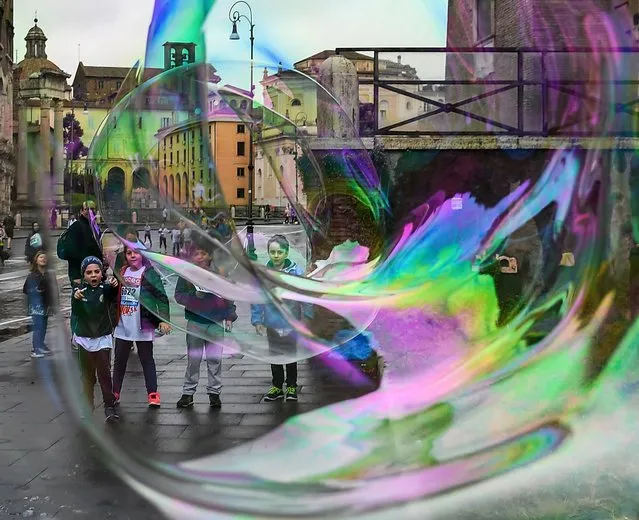 Children play with giant soap bubbles blown by a man for tourists and children on April 7, 2019 in Rome. (Photo by Vincenzo Pinto/AFP Photo)