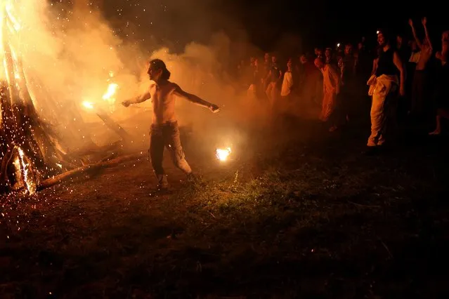 A man dances with fire around the main fire while attending the Shypit festival in the Carpathian Mountains on July 06, 2022 in Podobovets, Ukraine. (Photo by Scott Olson/Getty Images)