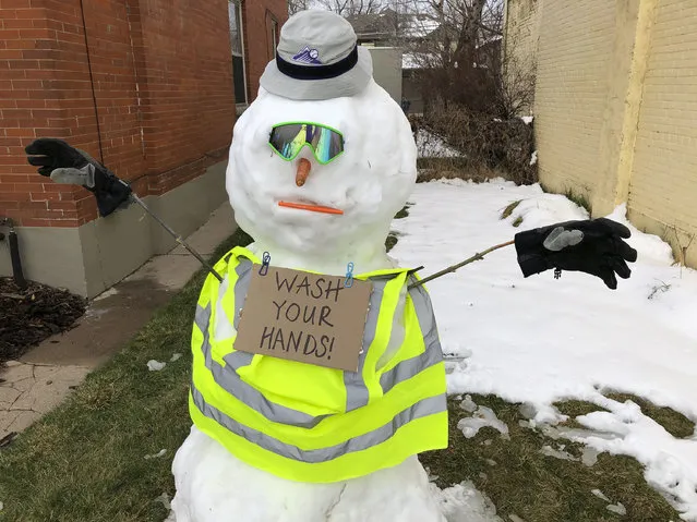 Built after Friday's snow, a snowman in front of a home on south Washington Street wears a sign carrying a message of advice as residents deal with the spread of coronavirus Saturday, March 21, 2020, in Denver. (Photo by David Zalubowski/AP Photo)