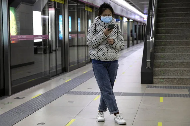 In this April 1, 2020, photo, a woman waits for her train at a subway station after entering with a green pass in Wuhan in central China's Hubei province. Life in China post-coronavirus outbreak is ruled by a green symbol on a smartphone screen. Green signifies the “health code” that says the user is symptom-free. It is required to board a subway, check into a hotel or enter Wuhan, the city where the global pandemic began. (Photo by Ng Han Guan/AP Photo)