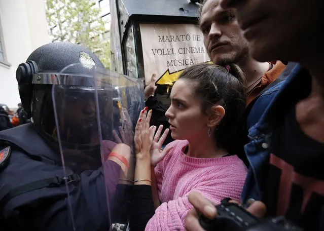 Spanish police push people with a shield outside a polling station in Barcelona, on October 1, 2017, on the day of a referendum on independence for Catalonia banned by Madrid. More than 5.3 million Catalans are called today to vote in a referendum on independence, surrounded by uncertainty over the intention of Spanish institutions to prevent this plebiscite banned by justice. (Photo by Pau Barrena/AFP Photo)