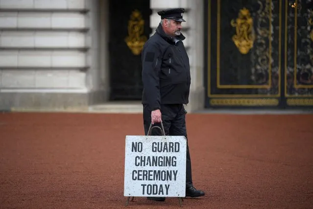 A member of staff holds a board reading “No changing of the guard ceremony today” in the courtyard of Buckingham palace, central London, on September 8, 2022. Fears grew on September 8, 2022 for Queen Elizabeth II after Buckingham Palace said her doctors were “concerned” for her health and recommended that she remain under medical supervision. The 96-year-old head of state – Britain's longest-serving monarch – has been dogged by health problems since last October that have left her with difficulties walking and standing. (Photo by Daniel Leal/AFP Photo)