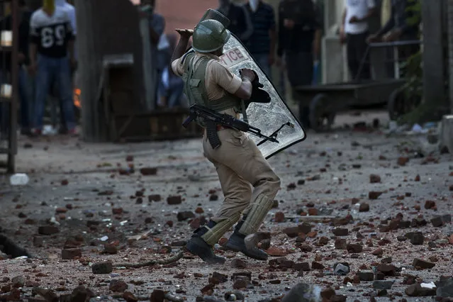An Indian paramilitary soldier reacts to avoid being hit by stones thrown at him by Kashmiri protesters during a protest in Srinagar, Indian controlled Kashmir, Thursday, July 28, 2016. Authorities lifted a curfew in most of parts of Indian-controlled Kashmir but shops and businesses remained shut due to a strike called to protest Indian rule in the Himalayan region. (Photo by Dar Yasin/AP Photo)