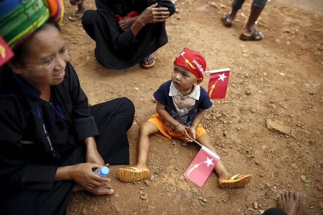 A girl holds National League for Democracy party flags as she waits for Myanmar pro-democracy leader Aung San Suu Kyi to arrive to give a speech on voter education at the Hsiseng township in Shan state, Myanmar September 5, 2015. (Photo by Soe Zeya Tun/Reuters)