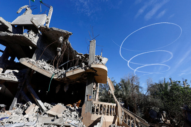 Israel aircrafts leave trails near the ruins of houses destroyed in Israeli strikes during the conflict, during a temporary truce between Hamas and Israel, in Khan Younis in the southern Gaza Strip on November 30, 2023. (Photo by Mohammed Salem/Reuters)