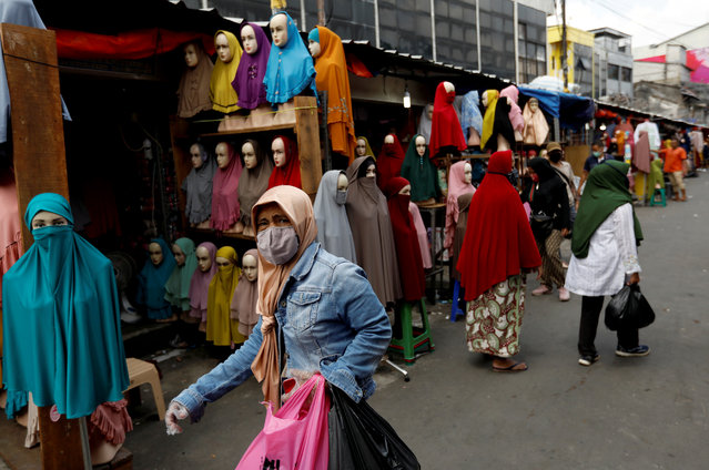 A woman wears a face mask and plastic gloves as she is shopping at a market selling hijabs and clothes for muslims, ahead of the holy fasting month of Ramadan, amid the spread of the coronavirus disease (COVID-19), in Jakarta, Indonesia, April 23, 2020. (Photo by Willy Kurniawan/Reuters)
