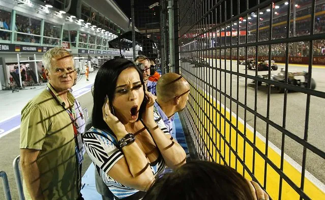 Singer Katy Perry holds her ears as she watches the cars race during the Singapore Formula One Grand Prix on the Marina Bay City Circuit, on September 23, 2012. (Photo by Edgar Su/Pool)