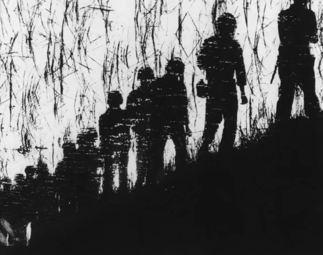 Vietnamese marines on patrol in Long An province, South Vietnam, are shown in reflection on water as they march along a dike at dawn on September 20, 1964. (Photo by AP Photo)