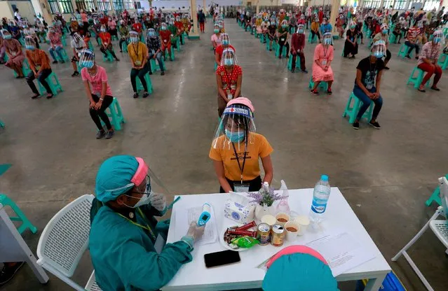 A military health worker (L) wearing protective gear takes the body temperature of a worker from the Tsang Yih Foot Wear company during a health check-up operation at the Hlaing Thar Yar industrial zone in an effort to contain the spread of the COVID-19 coronavirus in Yangon on May 16, 2020. (Photo by AFP Photo/Stringer)