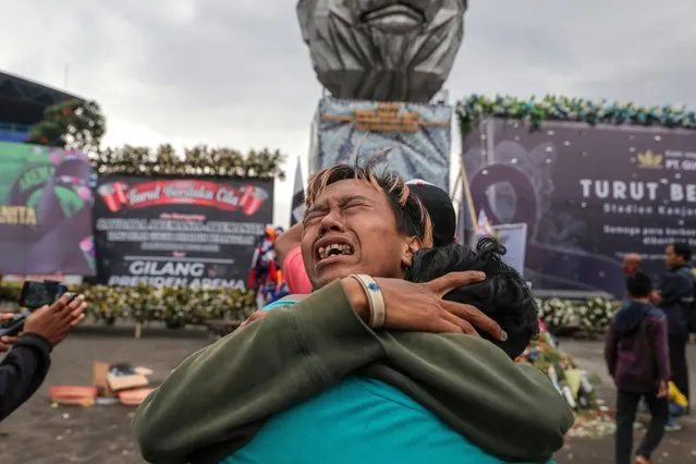 People react as they gather to remember the victims of a deadly stampede at Kanjuruhan Stadium, in Malang, East Java, Indonesia, 05 October 2022. The Indonesian president has ordered an investigation and audit to all soccer stadiums in the country, to ensure fans' safety after at least 131 people died in a riot and stampede following a soccer match between Arema FC and Persebaya Surabaya in East Java on 01 October 2022. (Photo by Mast Irham/EPA/EFE/Rex Features/Shutterstock)